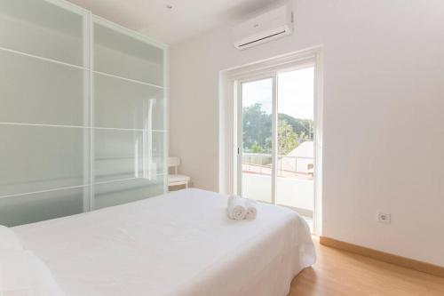 a white bedroom with a white bed and a window at 4 bedroom apartment near the beach! in Setúbal