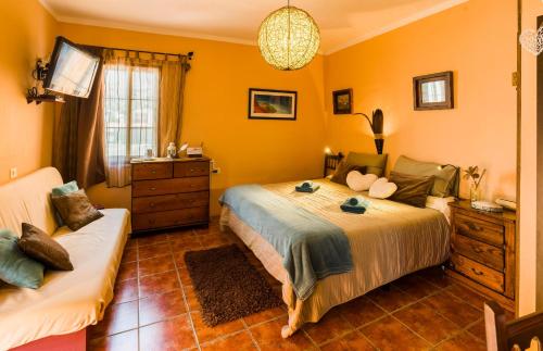 a bedroom with yellow walls and a bed and a couch at Casa Conchilla, La Casita in Valle Gran Rey