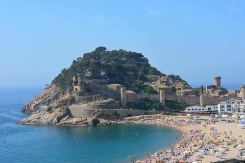 eine Gruppe von Menschen an einem Strand mit einer Insel in der Unterkunft Apartamento Terrassa 1 in Tossa de Mar