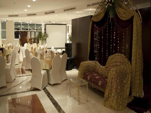 a banquet hall with white chairs and a table and a stage at Musherib Hotel in Doha