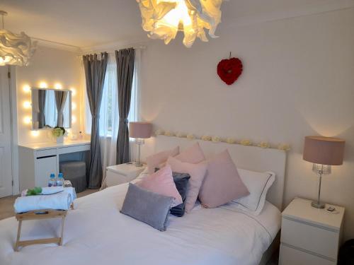 a bedroom with a white bed with pink and blue pillows at Sunny-side-up in St Austell