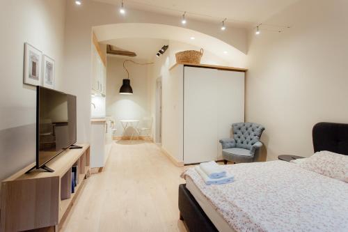 um quarto com uma cama, uma televisão e uma cadeira em COMMODUS apartment IX em Banská Štiavnica