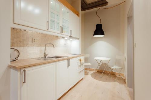 uma cozinha com armários brancos, um lavatório e uma mesa em COMMODUS apartment IX em Banská Štiavnica