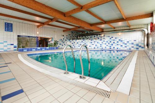 a swimming pool with blue and white tiles at Hotel Juan de la Cosa in Santoña