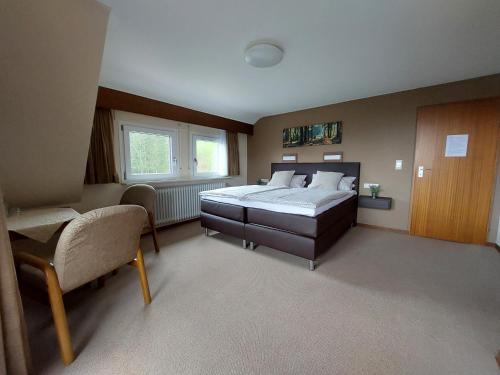 ein großes Schlafzimmer mit einem Bett und einem Stuhl in der Unterkunft Landhaus Waldeshöhe in Baiersbronn