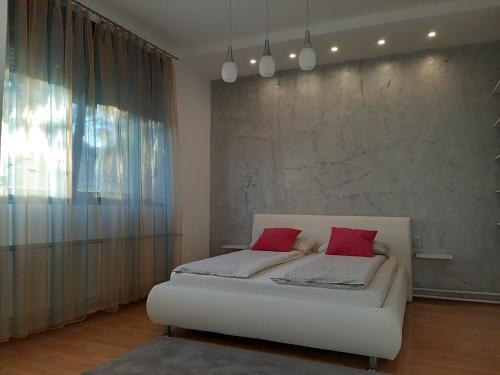 1 dormitorio con 1 cama blanca y 2 almohadas rojas en Ars Duo en Novi Sad