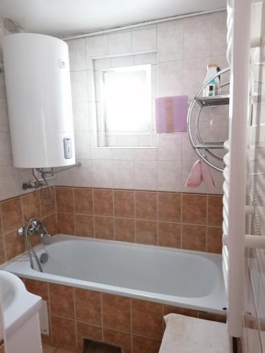 a bath tub in a bathroom with a window at Róza vendégszoba in Keszthely