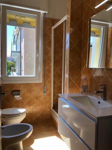 a bathroom with a toilet and a sink and a mirror at Ca' Adriana in Lido di Jesolo
