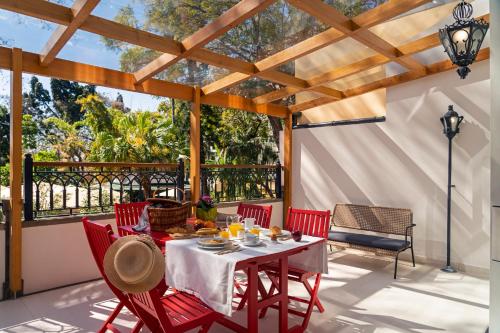 a patio with a table and red chairs and a large window at Madeira Gems Apartments in Funchal