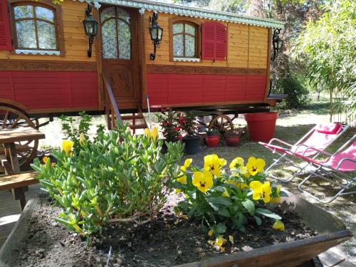 a tiny house in a garden with yellow flowers at Les roulottes Vesta in Léognan