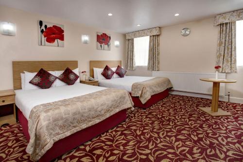 イルフォードにあるベスト ウエスタン グレーター ロンドンの赤いカーペットフロアの客室で、ベッド2台が備わります。