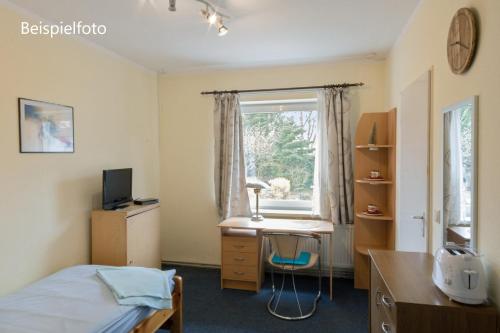 a bedroom with a desk and a bed and a window at Pension GP3, Zimmer mit Kochnische und Duschbad vor den Toren Berlins in Dallgow