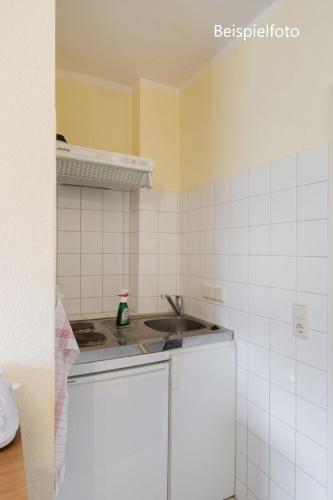 a kitchen with a sink and a white tiled wall at Pension GP3, Zimmer mit Kochnische und Duschbad vor den Toren Berlins in Dallgow