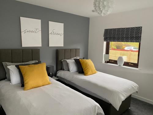 two beds with yellow pillows in a room at The apartment at Glendaruel in Portree