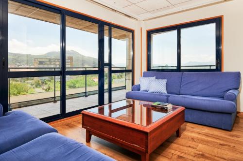 a living room with a blue couch and a coffee table at Hotel Juan de la Cosa in Santoña