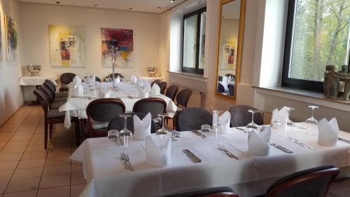 a room with tables and chairs with white tablecloths at Paolos Seehotel Mardorf in Mardorf