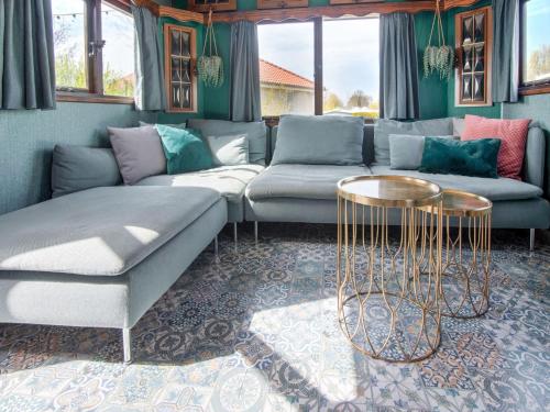 een woonkamer met een bank en 2 tafels bij Ibiza style chalet in Brouwershaven with lounge terrace in Brouwershaven