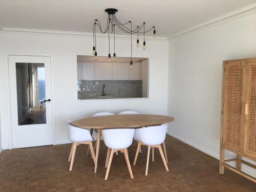 a dining room with a wooden table and white chairs at Residentie Majestic in Middelkerke