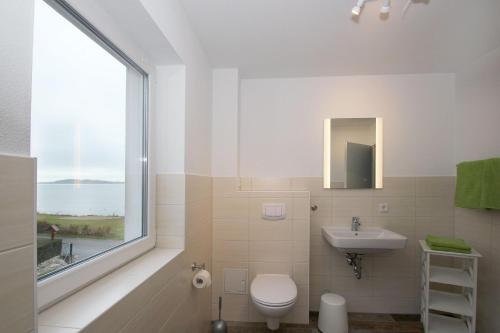 a bathroom with a toilet and a sink and a window at F-1037 Ferienhaus Neuendorf Haus Terrasse, Gartennutzung, Meerblick in Lauterbach