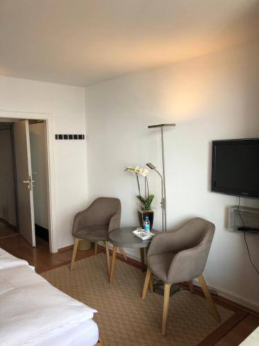 a hotel room with a table and two chairs and a tv at Paolos Seehotel Mardorf in Mardorf