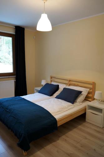 a bedroom with a large bed with blue pillows at Trzy Sosny Płaska in Płaska