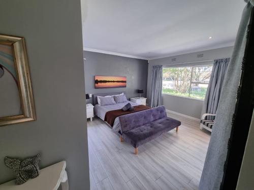 a bedroom with a bed and a couch and a window at Vaal River House @ Lochvaal in Vanderbijlpark