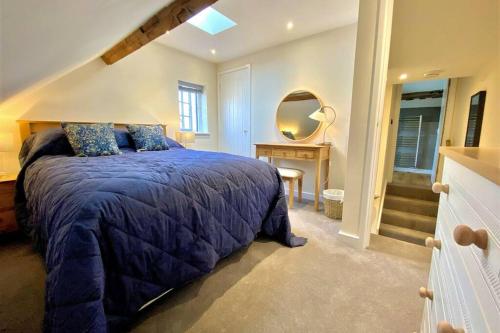 a bedroom with a bed with a blue comforter and a mirror at Tilly's a perfect apartment in the Market Town of Ledbury in Ledbury