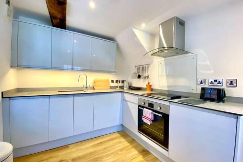 a kitchen with white cabinets and a stove top oven at Tilly's a perfect apartment in the Market Town of Ledbury in Ledbury