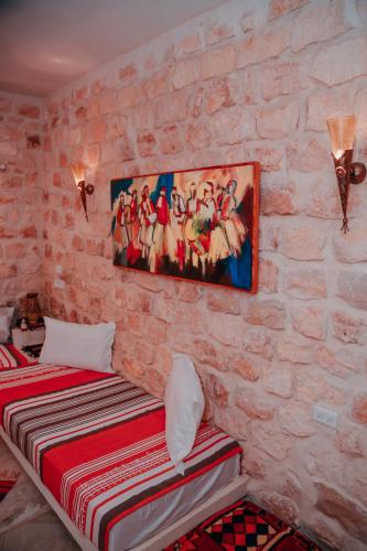 a bedroom with two beds and a painting on the wall at Dar Ayed Tamezret in Tamezret