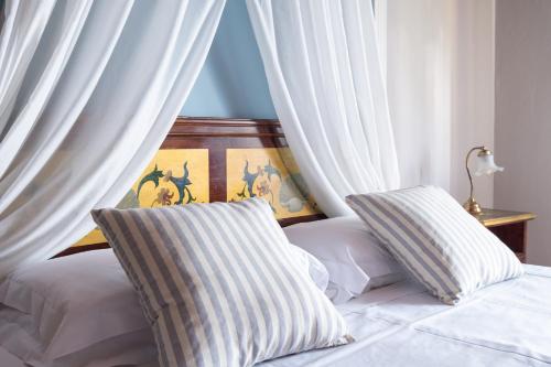a bedroom with white curtains and a bed with two pillows at Villa Pitiana in Donnini