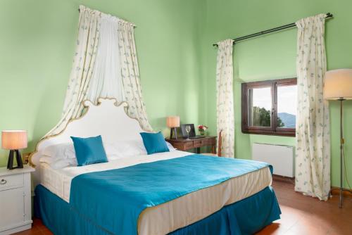 a bedroom with a bed with blue sheets and a window at Villa Pitiana in Donnini