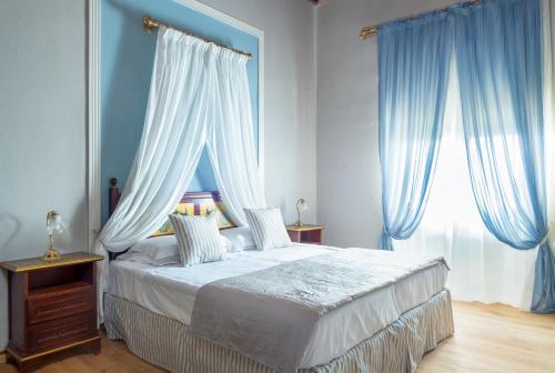 a bedroom with a large bed with blue curtains at Villa Pitiana in Donnini