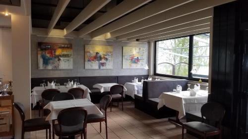 une salle à manger avec des tables et des chaises blanches dans l'établissement Paolos Seehotel Mardorf, à Mardorf
