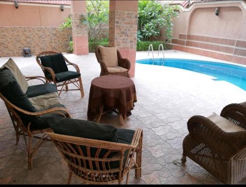 a group of chairs and a table next to a pool at Hidden Gem with pool access in New cairo in Cairo