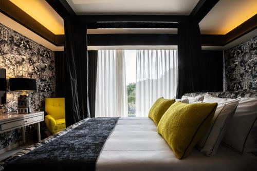 a bedroom with a large bed with yellow pillows at Vinha Boutique Hotel - The Leading Hotels of the World in Vila Nova de Gaia
