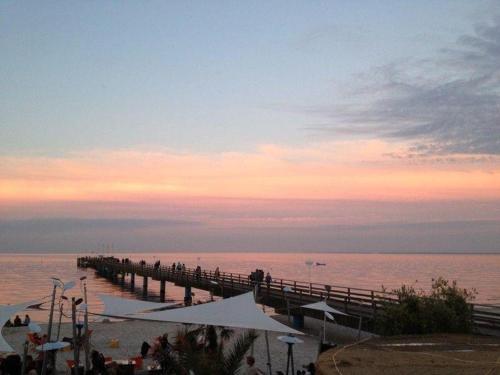 un muelle en la playa con gente caminando en él en HAF-OGL-Gaestehaus-Starke, en Haffkrug