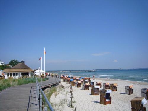plaża z kilkoma krzesłami i oceanem w obiekcie HAF-OGL-Gaestehaus-Starke w mieście Haffkrug