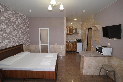 a bedroom with a large bed and a kitchen at Апартаменты DeMir in Adler