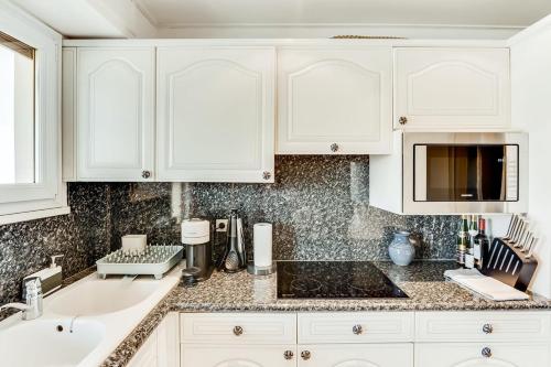 une cuisine avec des armoires blanches, un évier et un micro-ondes dans l'établissement Petit Juas Apartment, à Cannes