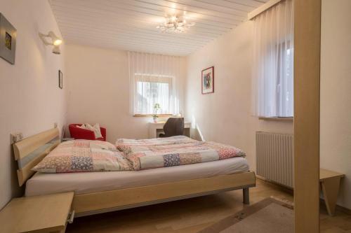 a bedroom with a bed and a desk and a window at Haus Schneider in Kressbronn am Bodensee