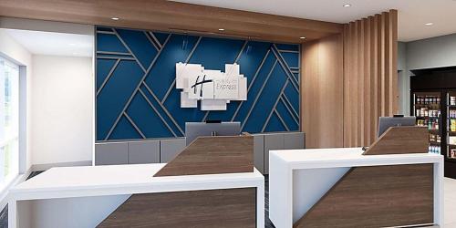 a lobby with two tables and a blue wall at Holiday Inn Express & Suites - Harrisonburg University Area by IHG in Harrisonburg