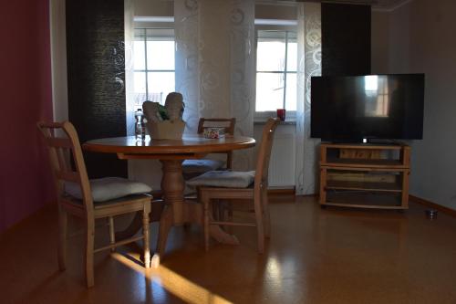 a dining room table with chairs and a television at Zimmer Lisa in Förbau