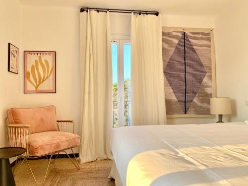 a bedroom with a bed and a chair and a window at L'Écurie Du Castellas in Ramatuelle