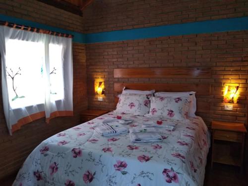 a bedroom with a bed with a floral bedspread and a window at Chalé da Sorte in Gonçalves
