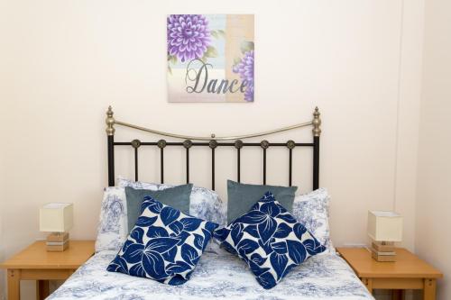 um quarto com uma cama com almofadas azuis e brancas em Merlin Cottages em Llandovery