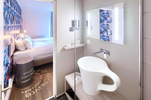 a small bathroom with a sink and a mirror at The Residence Hotel Geneva Airport in Ferney-Voltaire