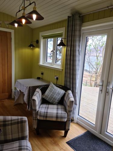 a room with a table and a chair and a window at The bay ,luxury shepherds hut, in Dundonnell