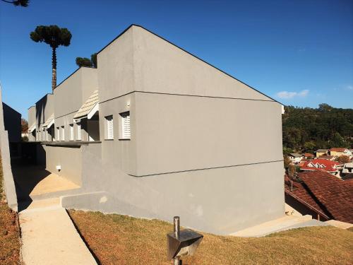 a white building with a tree in the background at Winter Garden - Guest House - Campos Do Jordão in Campos do Jordão