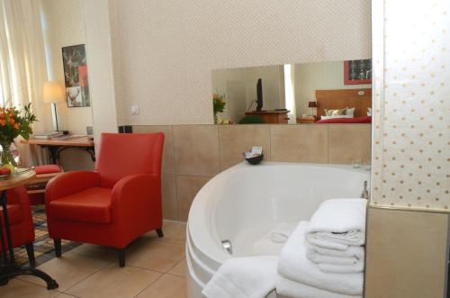 a bathroom with a red chair and a bath tub at Boutique Hotel Schieferhof in Neuhaus am Rennweg