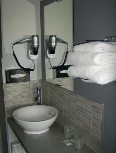 La salle de bains est pourvue d'un lavabo et d'un tas de serviettes. dans l'établissement Hôtel Restaurant Du Parc de la Colombière, à Dijon